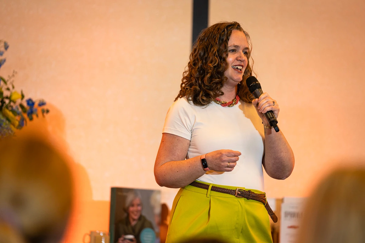 Jen speaking at an event, smiling as she talks with a microphone